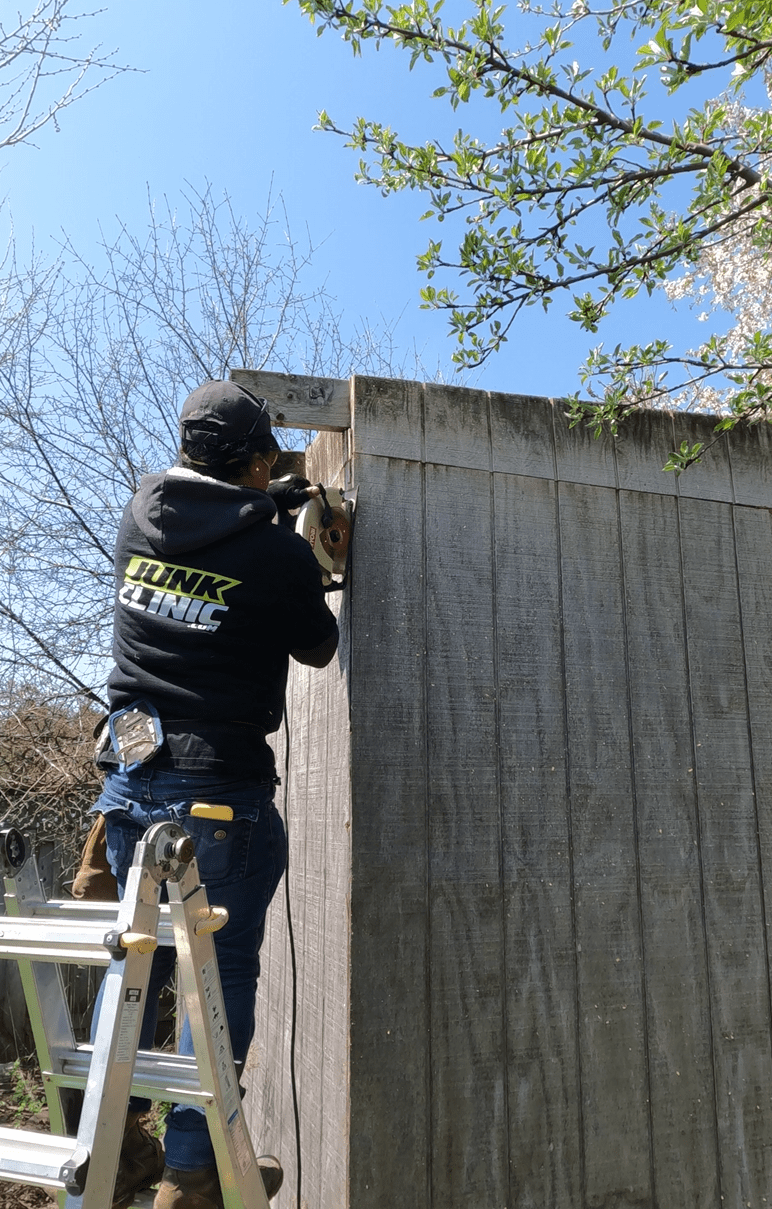 JUNKCLINIC team member sawing a wooden wall during a shed demolition