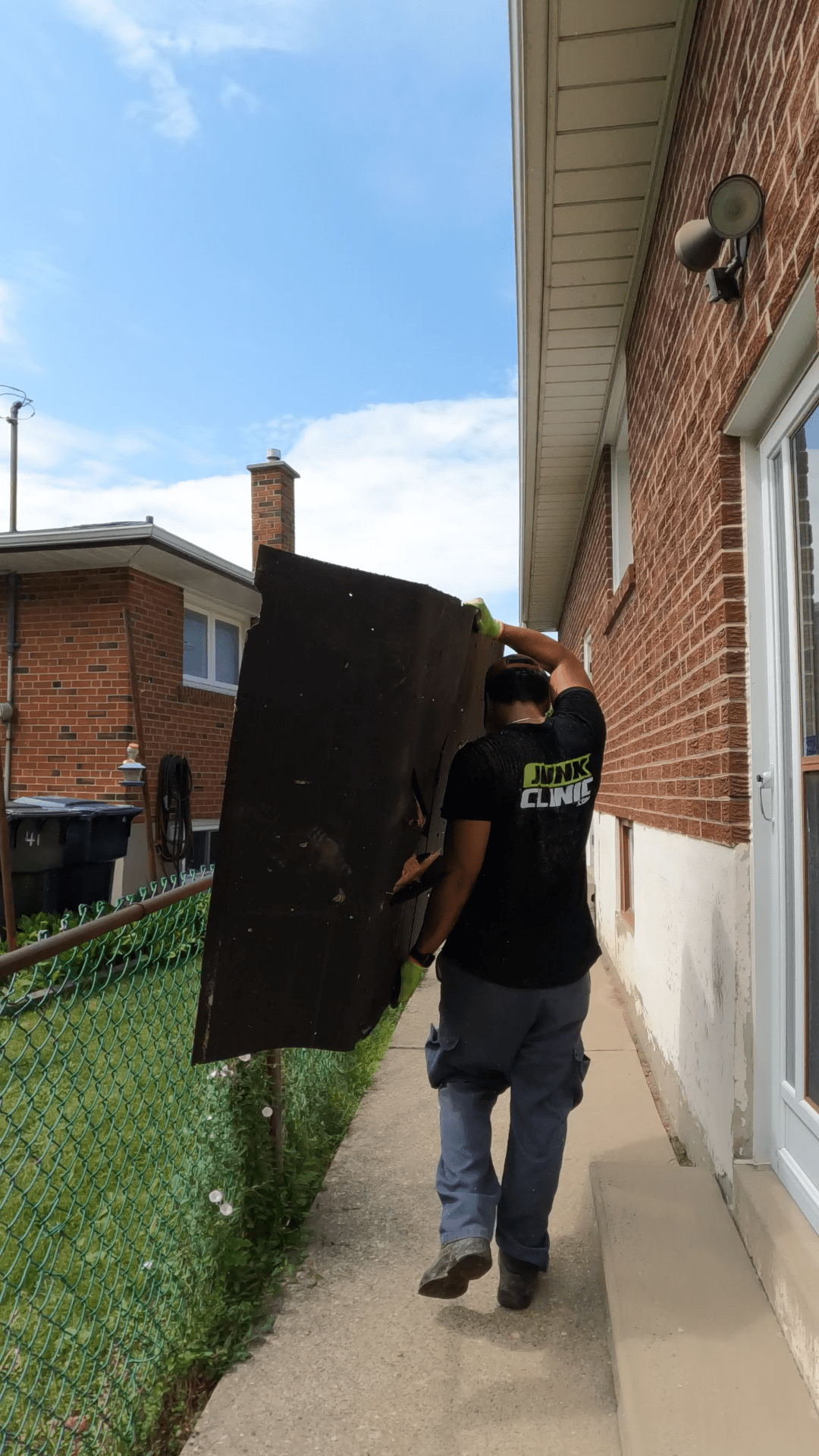 JUNKCLINIC team member lifting large piece of plywood
